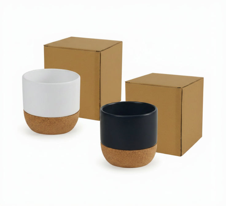 Two ceramic cups with cork bases and cardboard boxes on a white background
